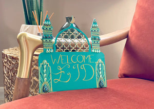 teal mosque shaped welcome sign with gold mesh dome and two minarets