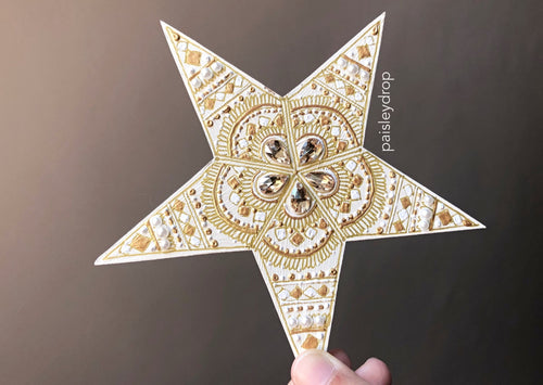 Hand painted ivory wall star. Painted with white and gold details. Five gold gems take up the centre designs.